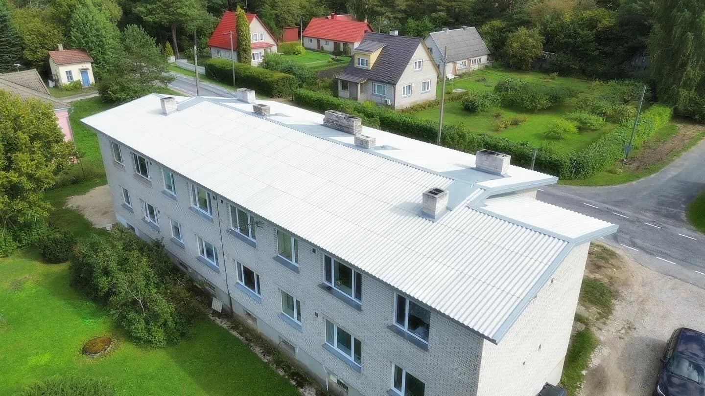 Aerofoto kolmekorruselisest korterelamust uue helehalli profiilplekk-katusega, ümbritsetud teiste punaste ja hallide katustega