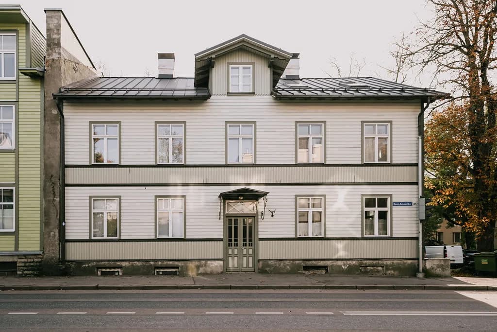 Ajalooline puitkortermaja Tallinna Suur-Ameerika tänaval, kreemikas voodrilaud ja tume katus, tänavavaade