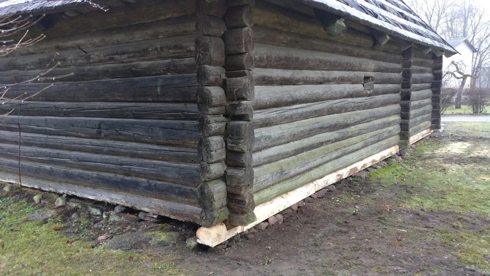 Vana tumeda palkhoone nurga lähivaade värskelt vahetatud heledate palkidega (palgivahetus)