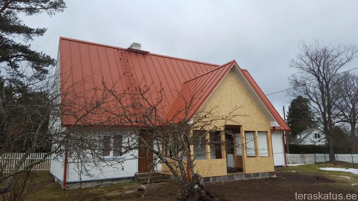 Valge talumaja erkoranži valtsplekk-katuse ja pooleldi valmis puitveranda lisaehitusega